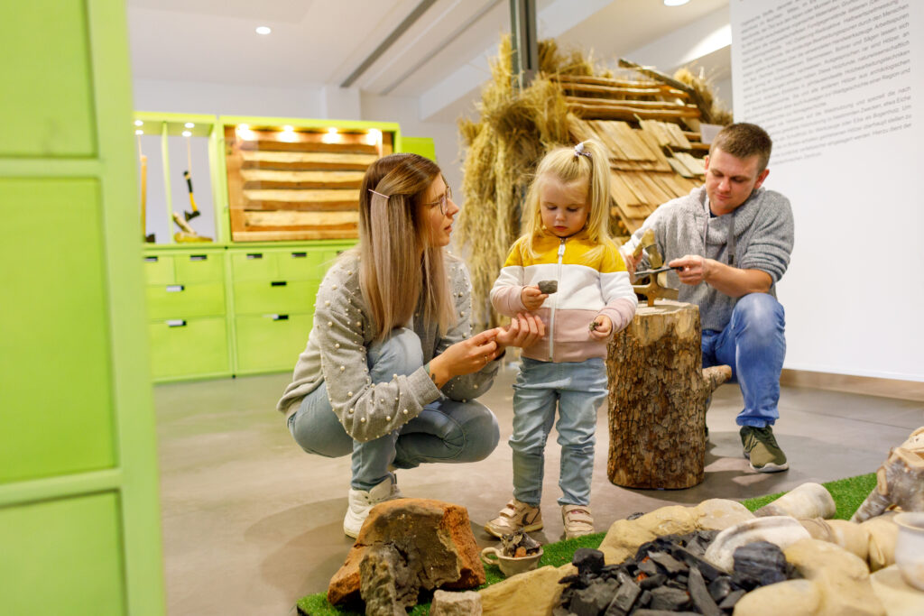 Ein Foto des Archäotechnischen Zentrums in Welzow. Zu sehen ist eine junge Familie, wie sie die historische Ausstellung anschaut. 