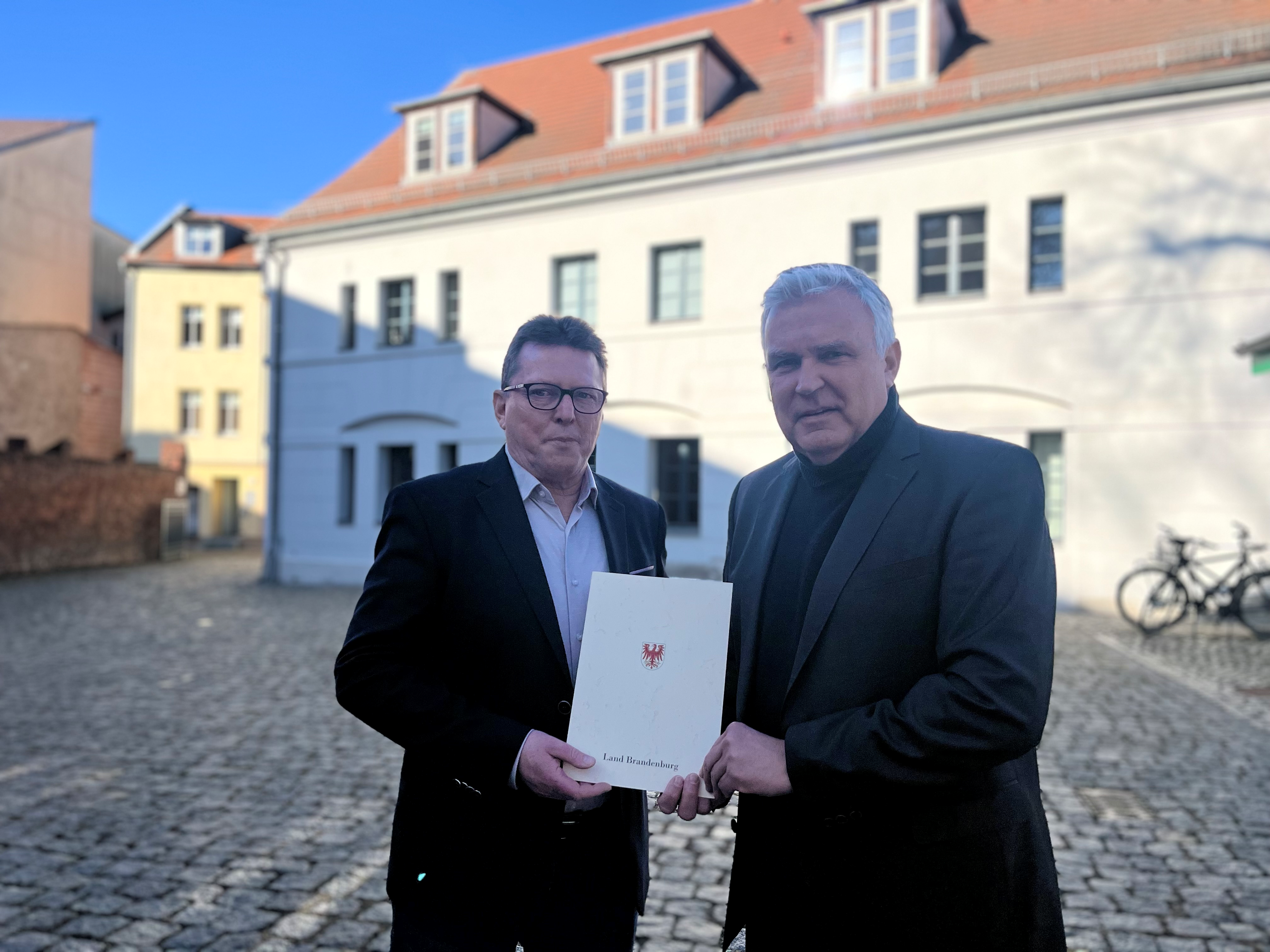 Heiko und Jahn und Dr. Klaus Freytag übergibt vor dem Hauptsitz der WRL-Geschäftsstelle den neuen Vertrag