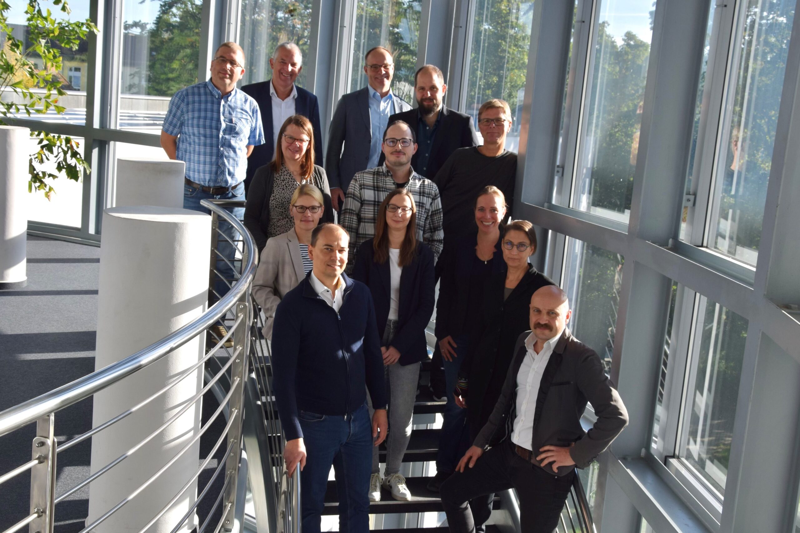 Ein Gruppenfoto der Arbeitsgruppe. Zu sehen sind 13 Menschen auf einer Treppe.