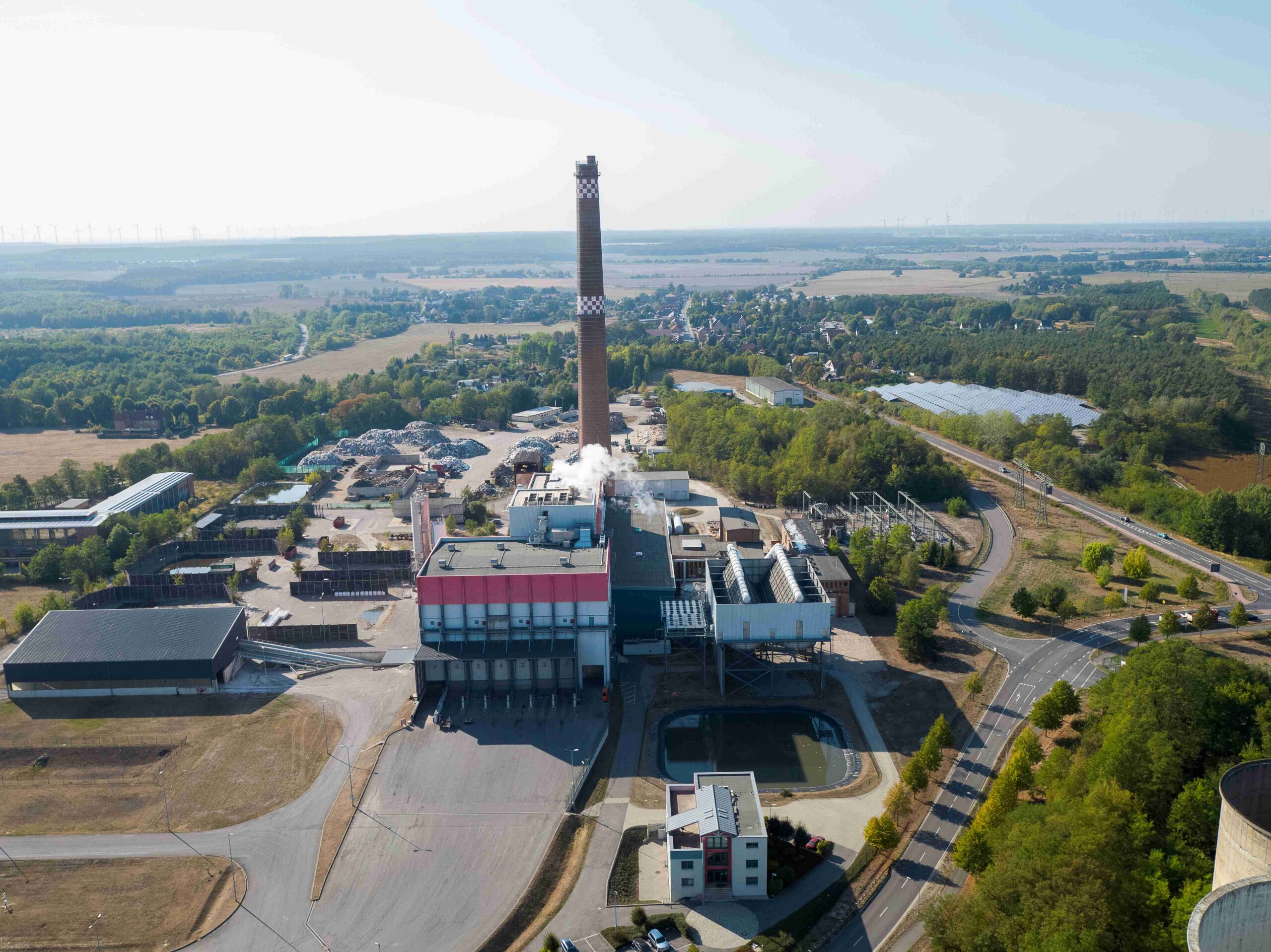Luftaufnahme vom Kraftwerk Sonne mit Schornstein, Solarpark im Hintergrund, an der Bundesstraße in Großräschen.