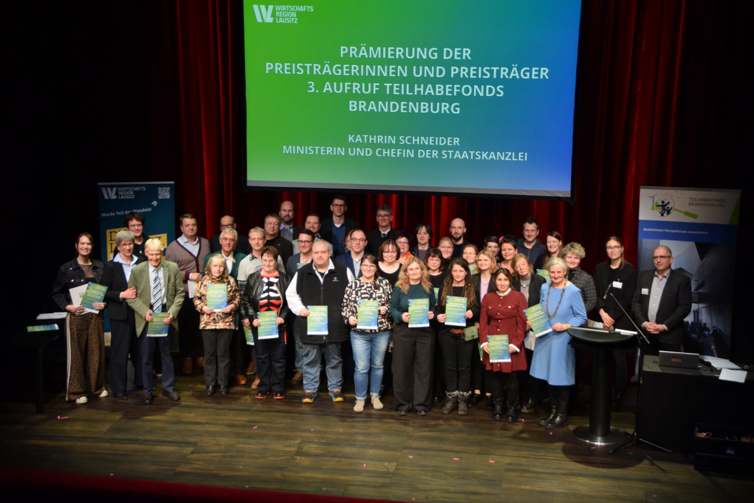 Gruppenfoto auf der Bühne mit den ausgezeichneten Projektinitiatorinnen und Projektinitiatoren des 3. Aufrufs bei der Prämierungsveranstaltu